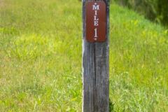 Mile marker in front of green grass portrait